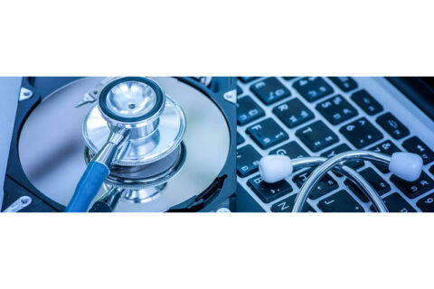 Stethoscope placed on a hard disk platter next to a laptop keyboard, symbolizing computer diagnostics and repair.