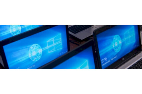 Multiple laptops displaying Windows login screens arranged on a desk.