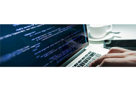 Laptop screen displaying lines of code with a person typing on the keyboard, representing programming and software development